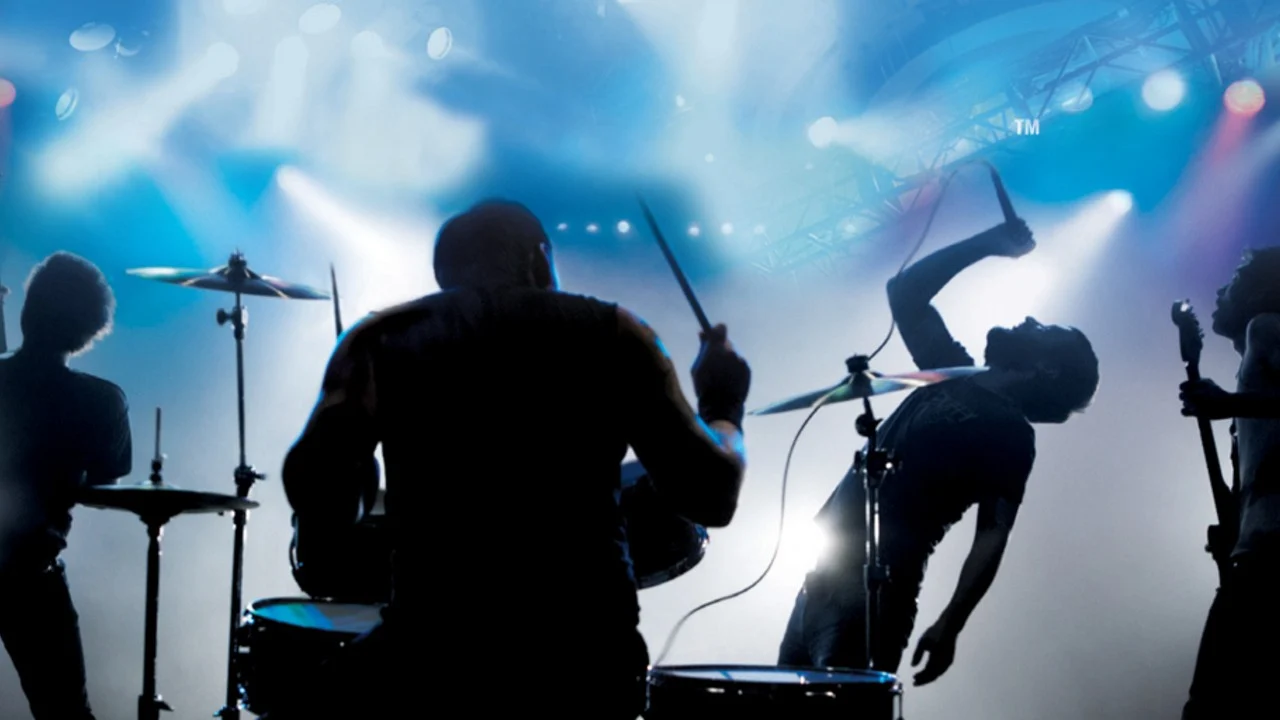 rock band on stage; drummer drumming, guy singing, two members with guitars.